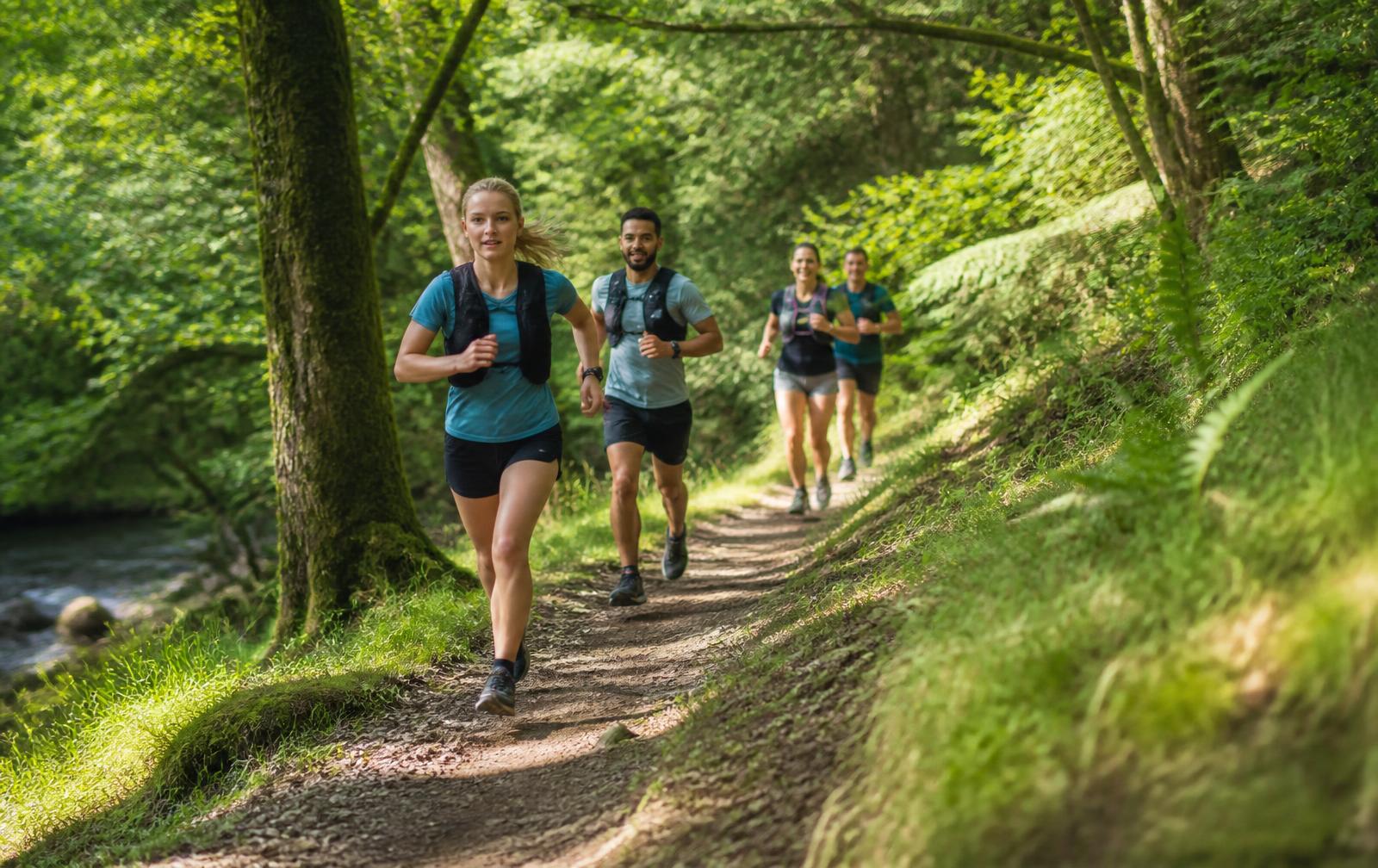 Trail runners racing through green British woodland